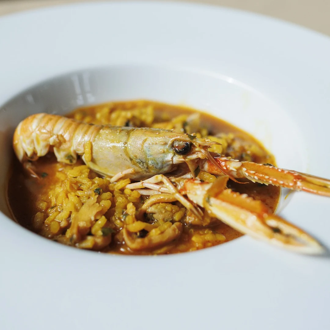Langoustine de la criée de Gandia servie sur du riz dans une assiette creuse blanche
