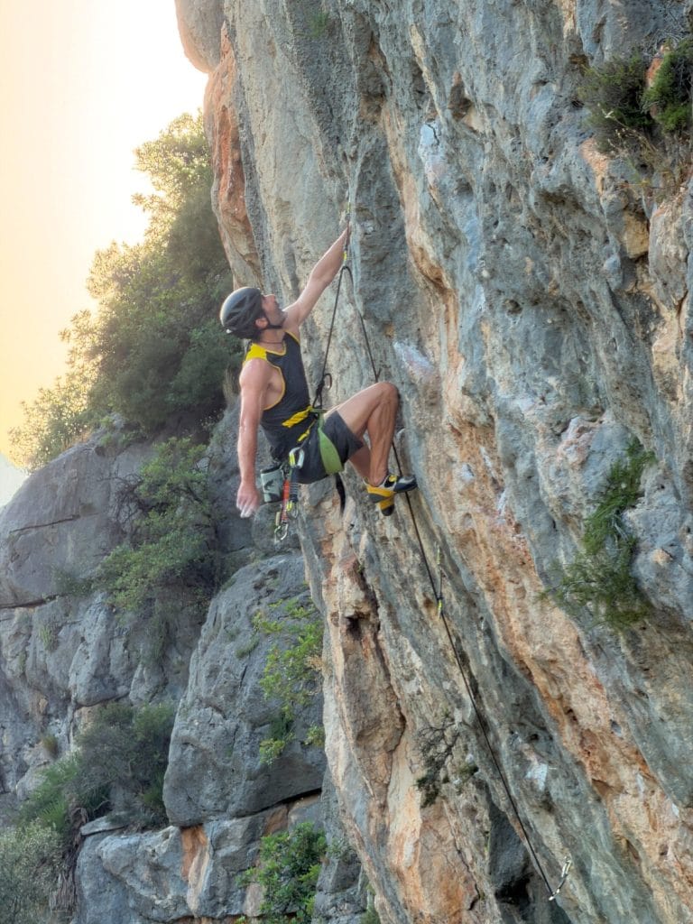 Grimpeur avec un casque gravissant une voie à la Penya Roja de Marxuquera