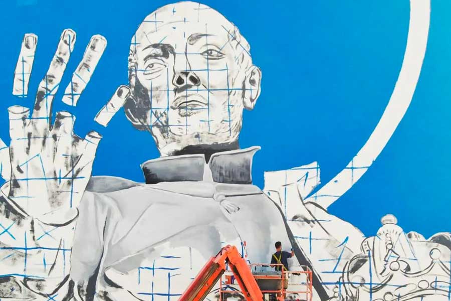 Diego As reportant l'esquisse de la fresque à l'aide d'une grille bleue depuis une nacelle élévatrice