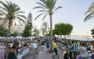 Stalls and visitors at Gandia’s summer market among palm trees beside the harbour