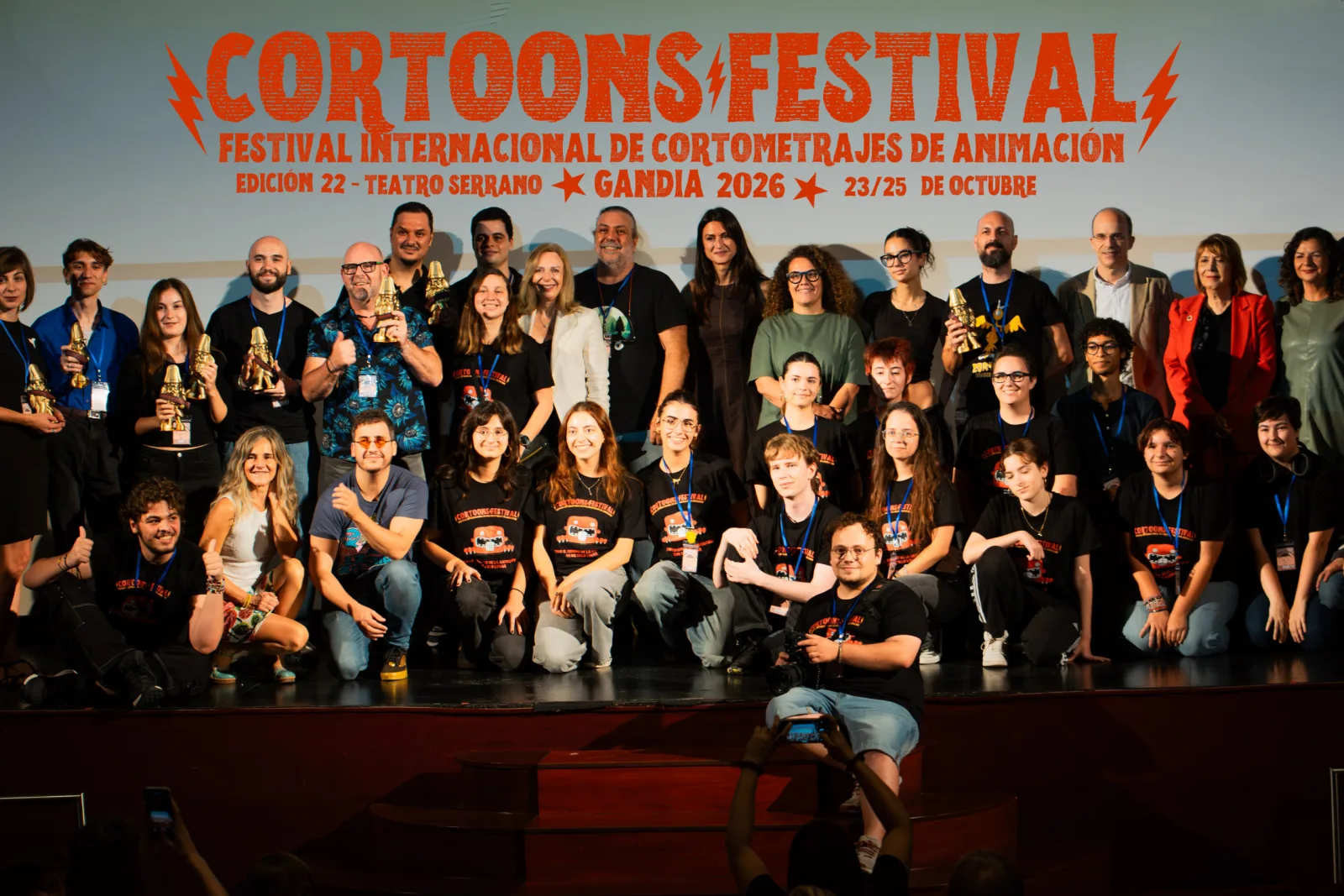 Group photo of Cortoons Festival award winners and team on stage with their trophies