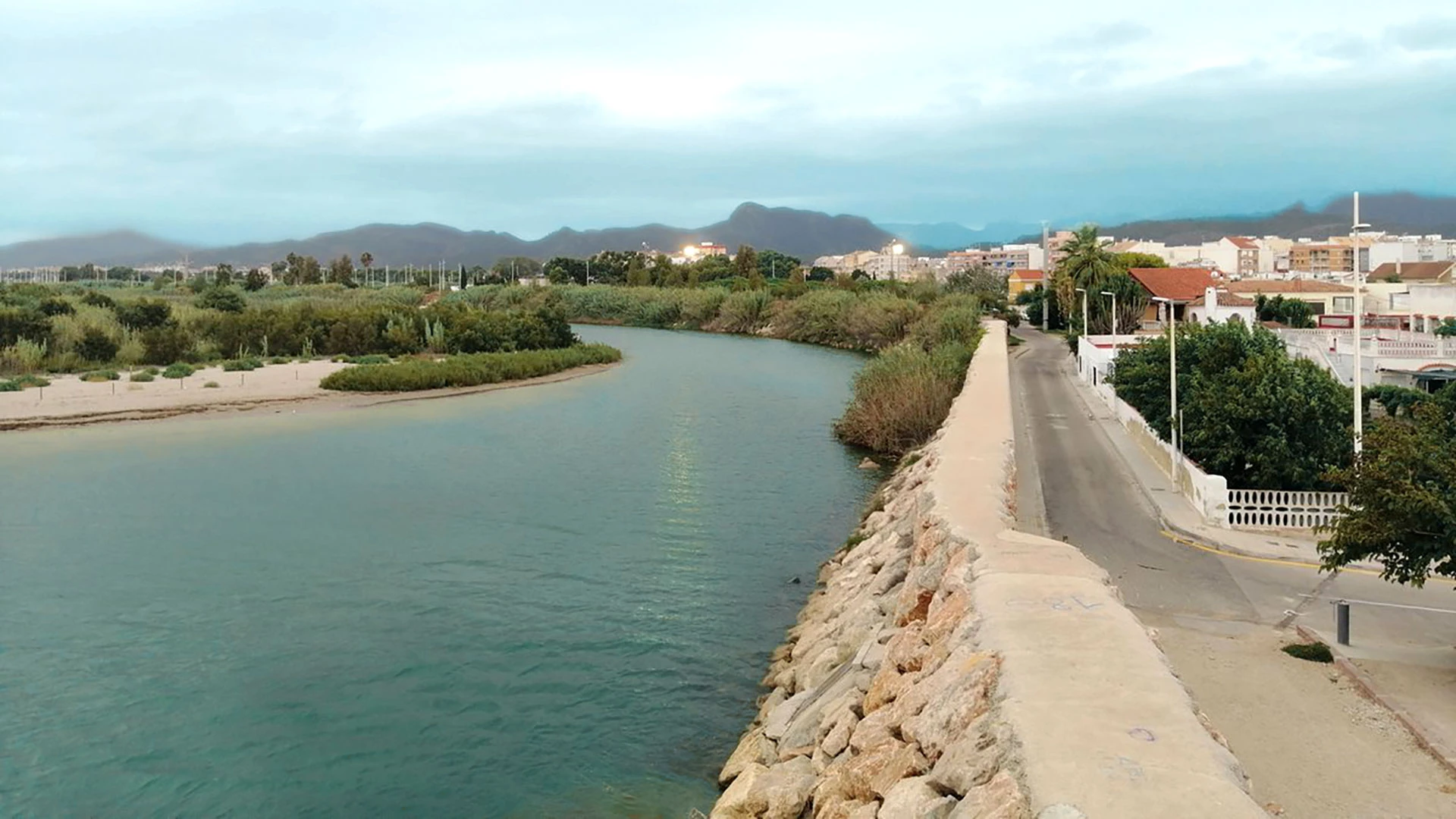 Cours final du fleuve Serpis le long de la rue et des petites maisons basses blanchies à la chaux de la colonie de Venècia à Gandia