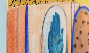 Detail of a work by Aleksandra Istorik from the “Surrealismo Dorado” exhibition: a blue hand inside an arch, with bands of gold leaf and blue strokes.
